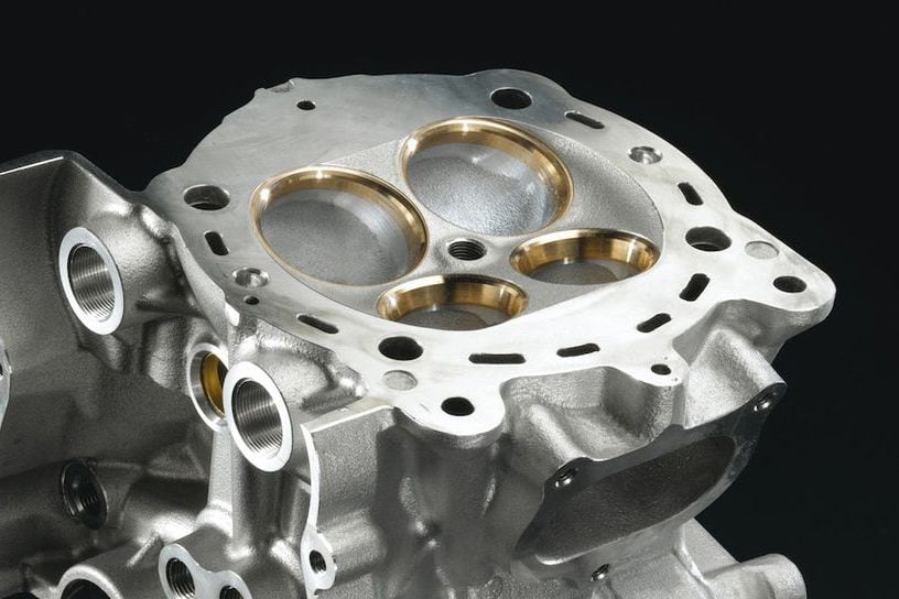 Aluminum cylinder heads need a hard material for the valves to seat against—here gold-colored oversize beryllium copper valve-seat rings are employed for use with titanium valves.